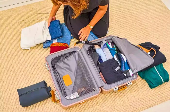 A person organizing belongings inside the TUMI 19 Degree Aluminum International Carry-on