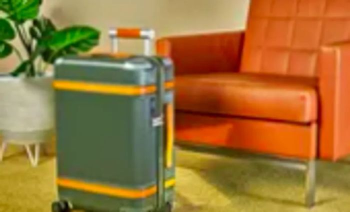 Paravel Aviator Carry-On Plus placed beside a chair and a plant on a carpet