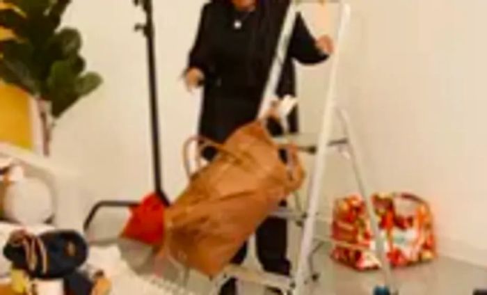 A person pushes a Leatherology Kessler Large Duffle off a step ladder