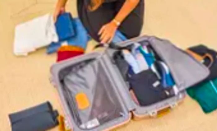 A person organizing their belongings inside the TUMI 19 Degree Aluminum International Carry-on