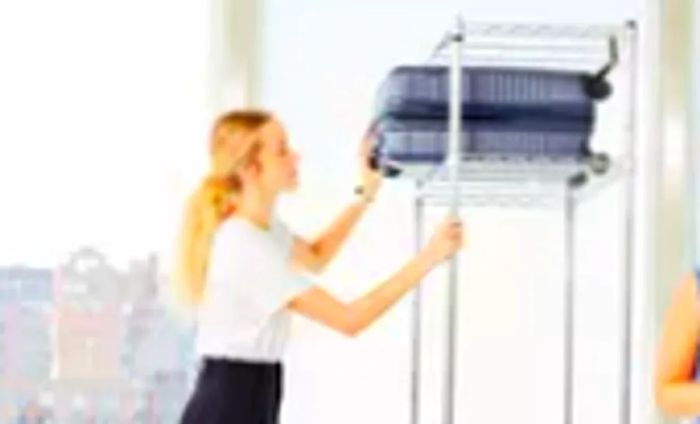 Individual places a carry-on from the Béis Hardside Luggage Set onto a high shelf, while another person looks on