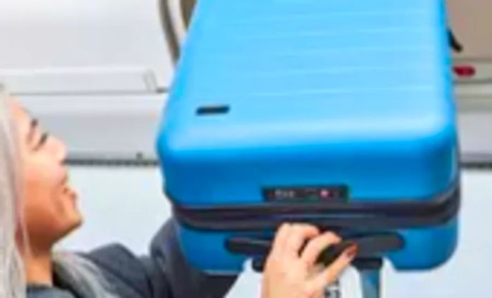 A person hoisting Away The Carry-on Flex into an overhead storage bin