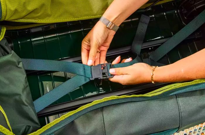 A person modifies the straps on the Away The Outdoor Rolling Duffel 85L