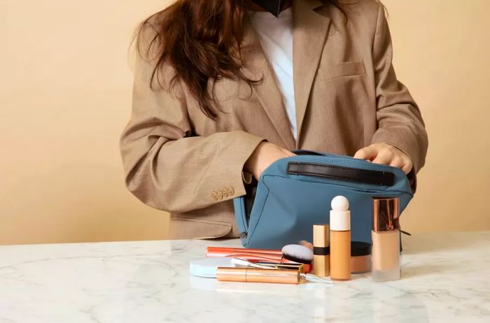 A woman applying makeup from the Away Large Toiletry Bag