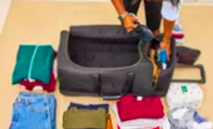 A person fills the Mark & Graham Terminal 1 Checked Rolling Duffle Bag