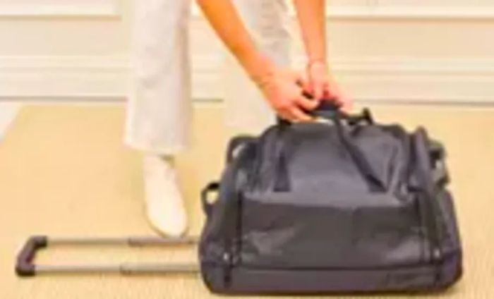 A traveler modifies the handle of the Solo Leroy Rolling Duffel