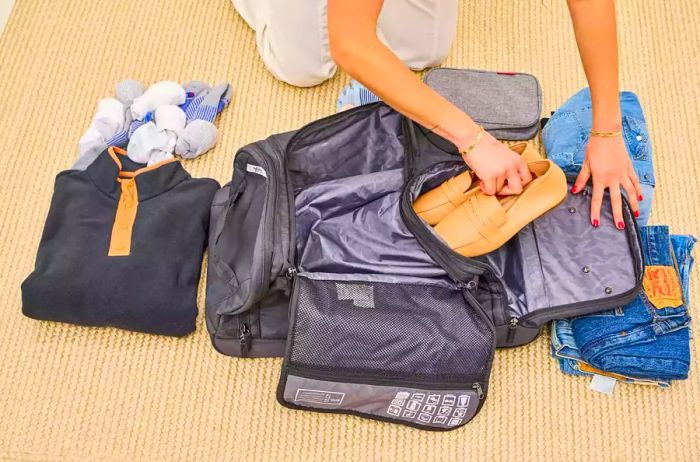 A person is packing shoes into the Solo Leroy Rolling Duffel