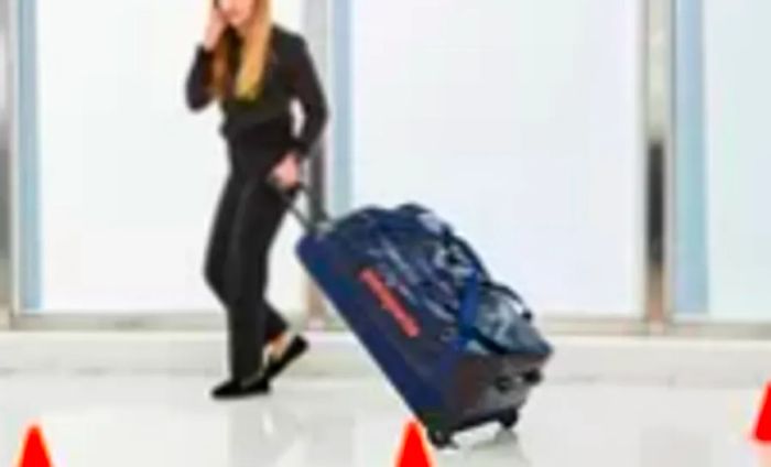 Individual maneuvering the Patagonia Black Hole Wheeled Duffel Bag 100L around cones during testing