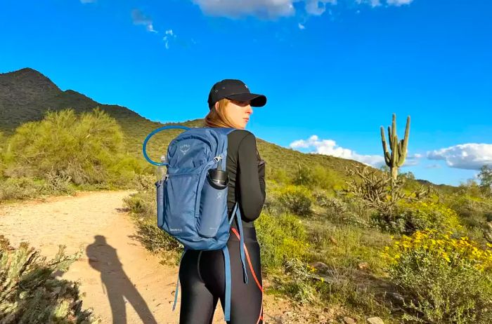 A woman trekking on a desert trail with an Osprey Daylite Plus Daypack.