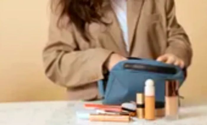 A woman applying makeup using the Away Large Toiletry Bag