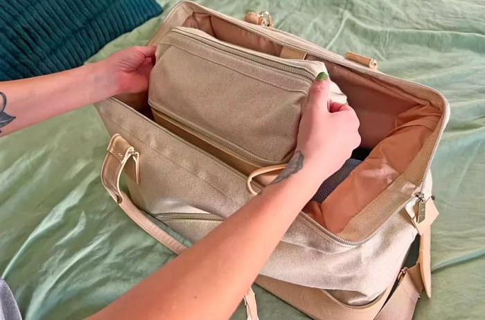 A person holds the Beis The Dopp Kit aloft