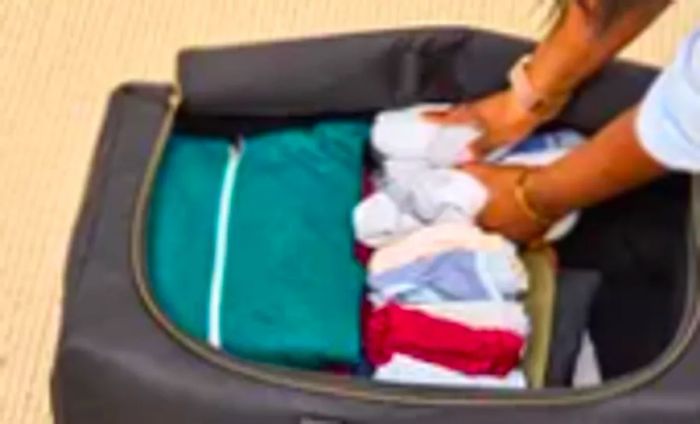 A person fills the Mark & Graham Terminal 1 Checked Rolling Duffle Bag