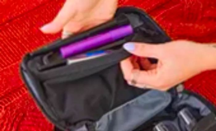 A person loads travel essentials into the Aer Travel Kit 2