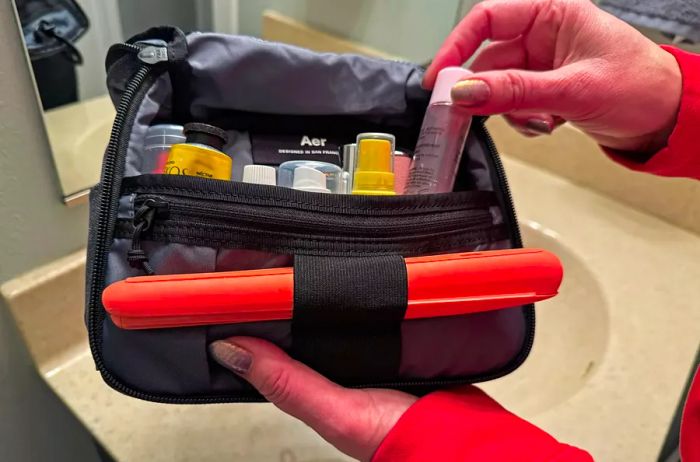 A person organizes travel essentials into the Aer Travel Kit 2