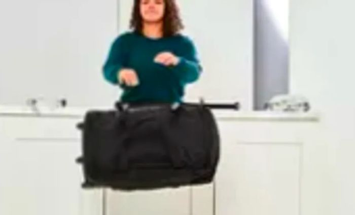 Person tossing the Vera Bradley Foldable Rolling Duffel Bag off a counter