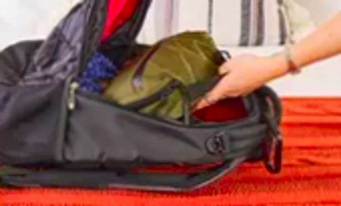 A person packs the Aer Travel Kit 2 into a backpack