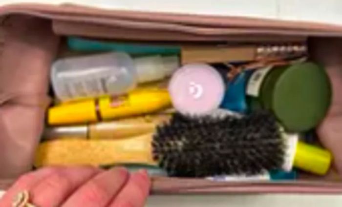 A person displays the LINE+ARC The Medium  L Dopp Kit, showcasing various toiletries