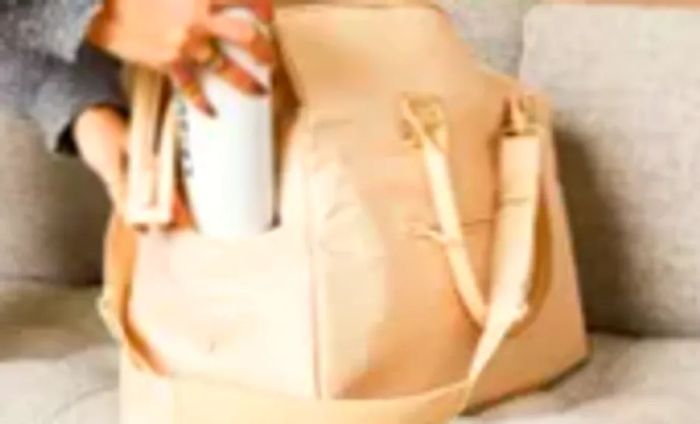 A person setting a water bottle atop the Béis The Commuter Duffel
