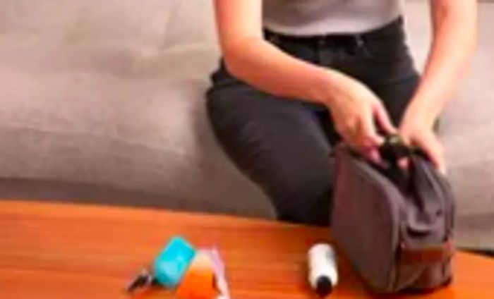 A hand is inserting travel-sized conditioner into a Bagsmart Toiletry Bag for Men.