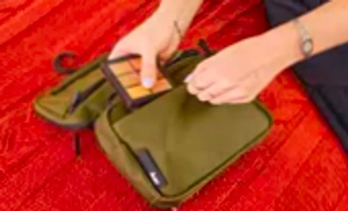 A person organizes makeup items inside the Aer Travel Kit 2