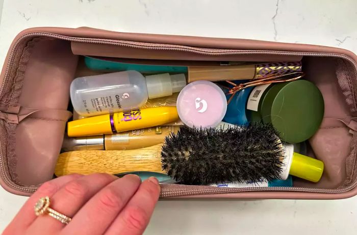 A person displays the LINE+ARC The Medium  L Dopp Kit, revealing a selection of toiletries inside.