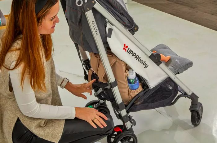 A person attaching the JuJuBe Zealous Backpack to a stroller