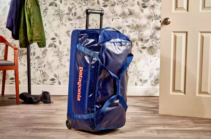 Patagonia Black Hole Wheeled Duffel Bag 100L showcased upright against a floral backdrop