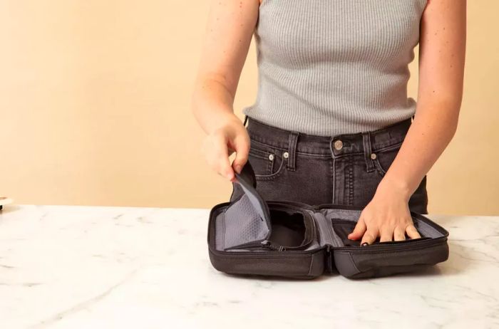 A hand is seen accessing one side of the Tumi Response Travel Kit's compartment.