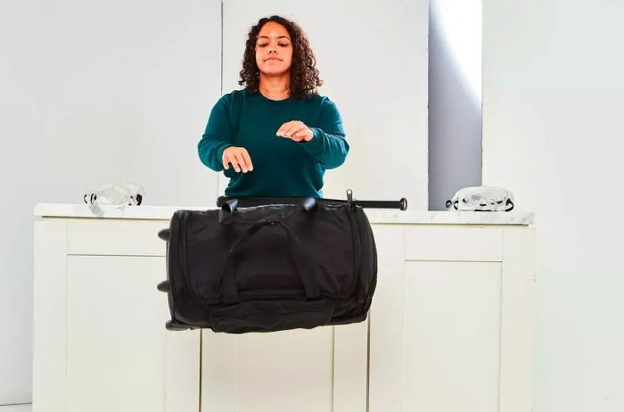 Person tossing the Vera Bradley Foldable Rolling Duffel Bag off a counter