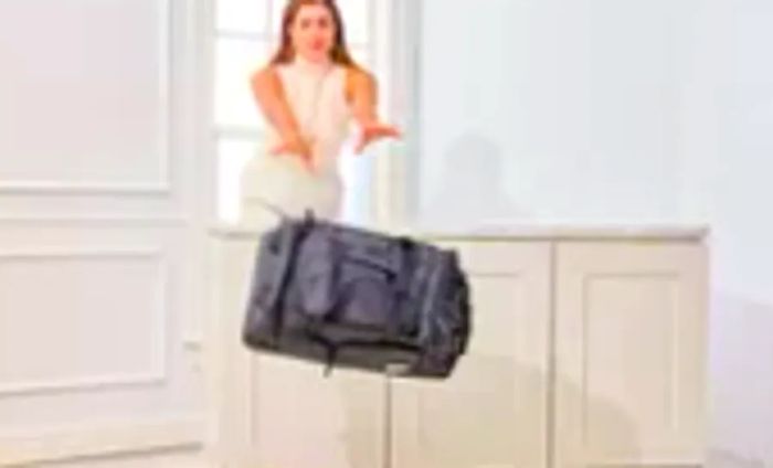 A traveler tosses the Solo Leroy Rolling Duffel off a table