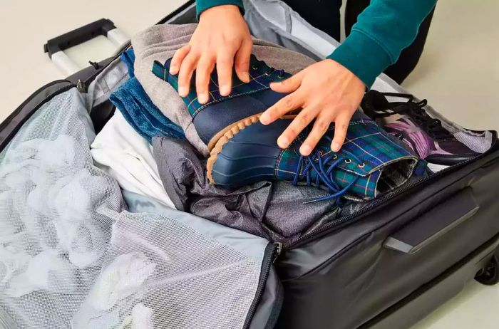 Individual loading items into the Thule Chasm Wheeled Duffel 32