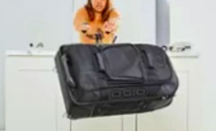 Individual tossing the Ogio Terminal Travel Bag off a counter to assess its durability