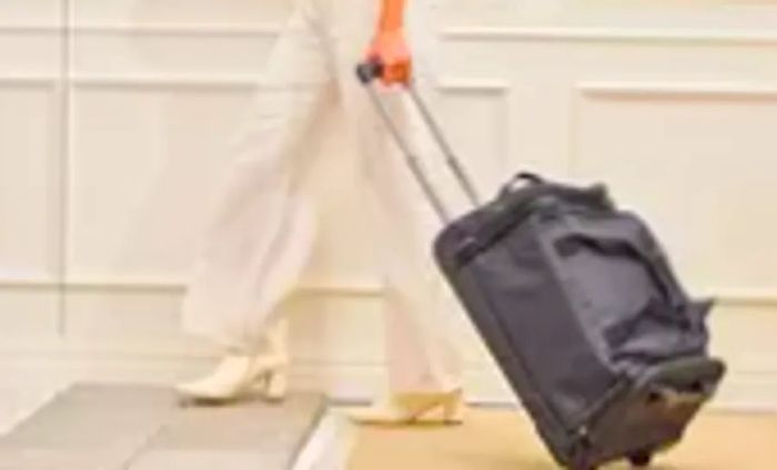 A traveler rolls the Solo Leroy Rolling Duffel across a rug