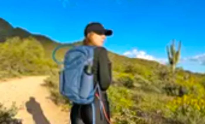 A woman hiking on a desert trail with the Osprey Daylite Plus Daypack.