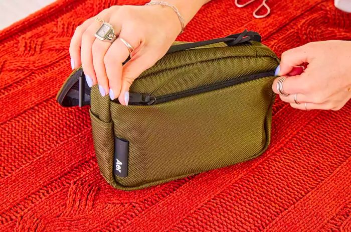 A person zips up the front pocket of the Aer Travel Kit 2