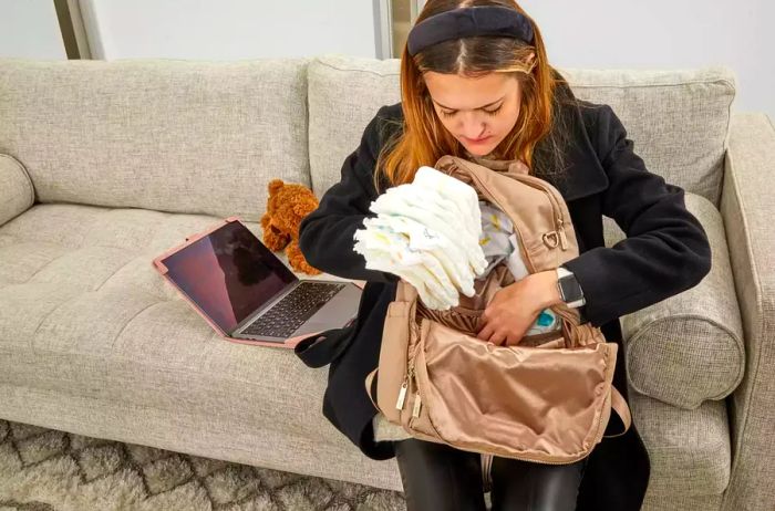 An individual loading diapers into the JuJuBe Zealous Backpack