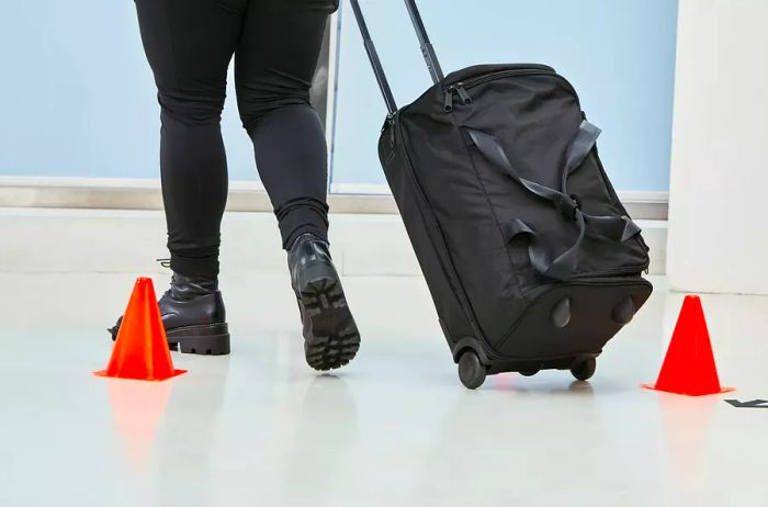 Person maneuvering the Vera Bradley Foldable Rolling Duffel Bag around cones