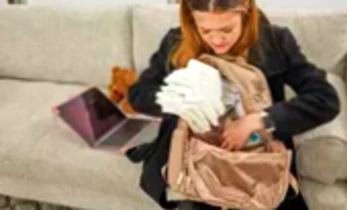 An individual loading diapers into the JuJuBe Zealous Backpack