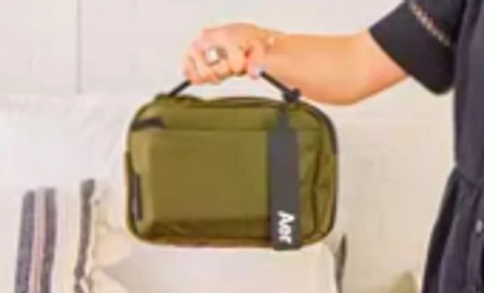 A person lifts the Aer Travel Kit 2 using its top handle