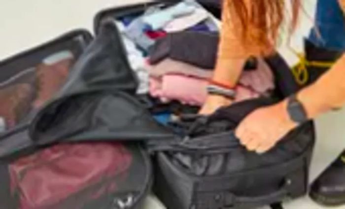 Individual loading clothes into the Ogio Terminal Travel Bag