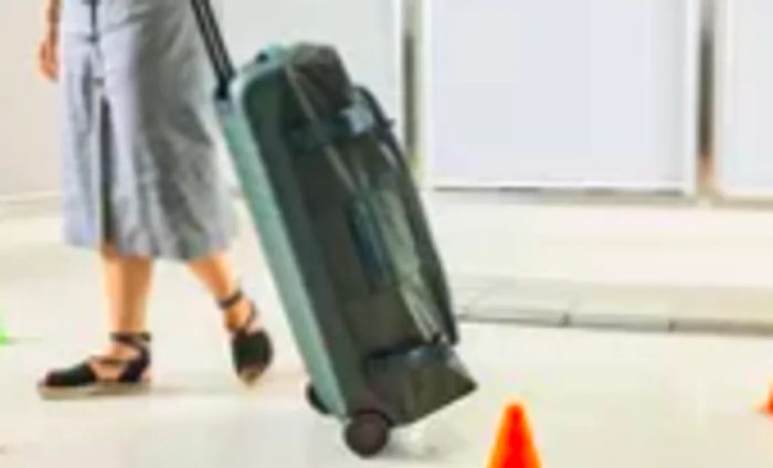 A person navigates the Away The Outdoor Rolling Duffel 85L through a series of cones