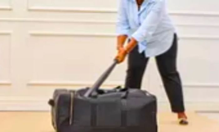 A person strikes the Mark & Graham Terminal 1 Checked Rolling Duffle Bag with a bat