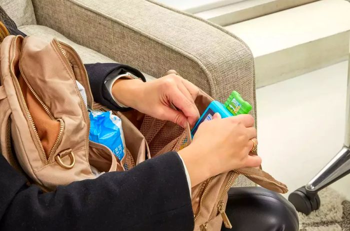 An individual adding an item to the JuJuBe Zealous Backpack