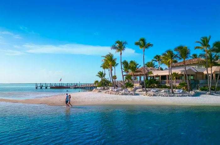 A couple strolling along the beach at Little Palm Island