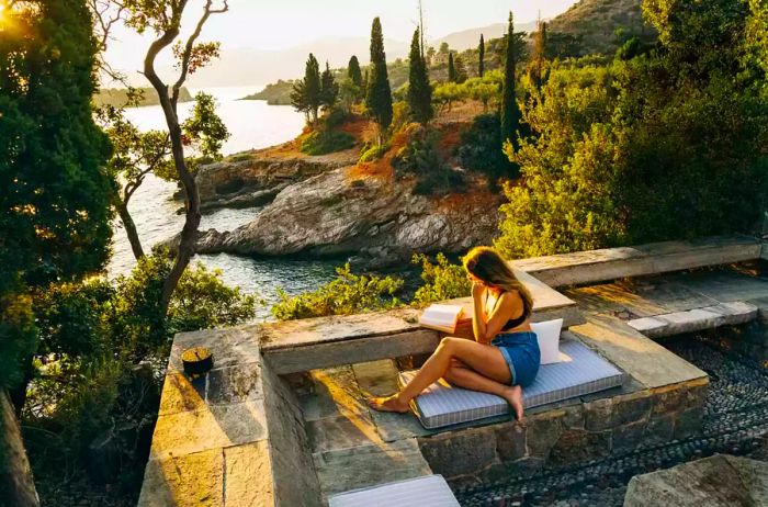 A woman enjoys a book on the terrace of a Kardamyli home, with breathtaking views of the sea