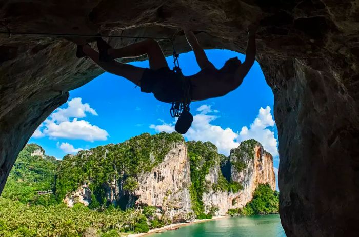 A climber ascends a rock cliff in Railay, Thailand.