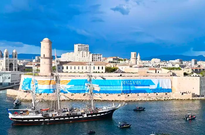 A historic sailing vessel bearing the Olympic flame arrives in Marseille