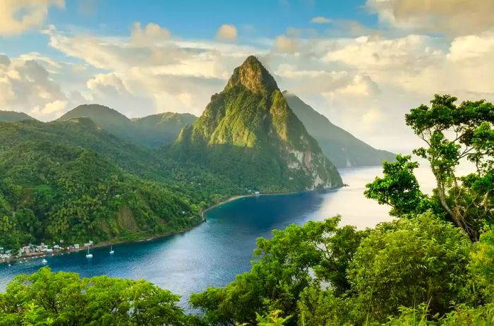 A stunning view of St. Lucia's Petit Piton and Gros Piton from an elevated vantage point, with the rainforest and Soufrière Bay in the foreground