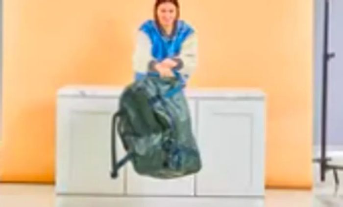 A person nudges the Away F.A.R. Duffle 70L off a table