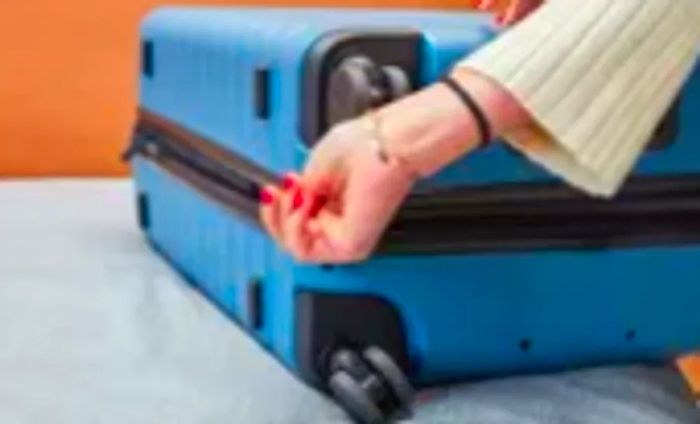 A person fastening the zipper on the Away medium carry-on